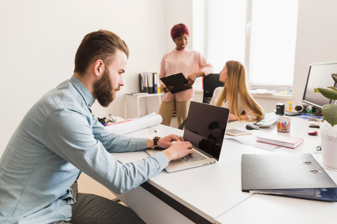 man-working-near-chatting-colleagues