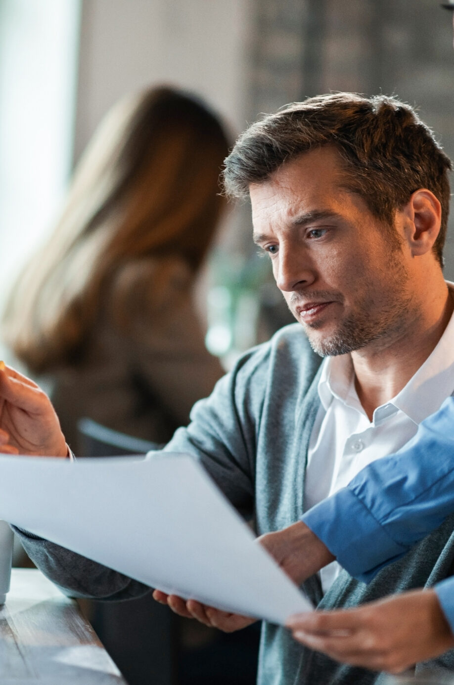 two-business-colleagues-examining-documents-while-working-together-office